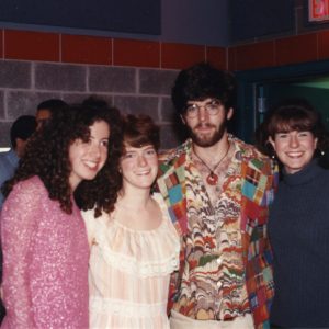 Four students stand with their arms around each other, smiling, at a 1994 concert in the Harris Center.